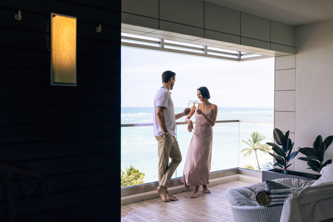 Couple having champagne on balcony with ocean view